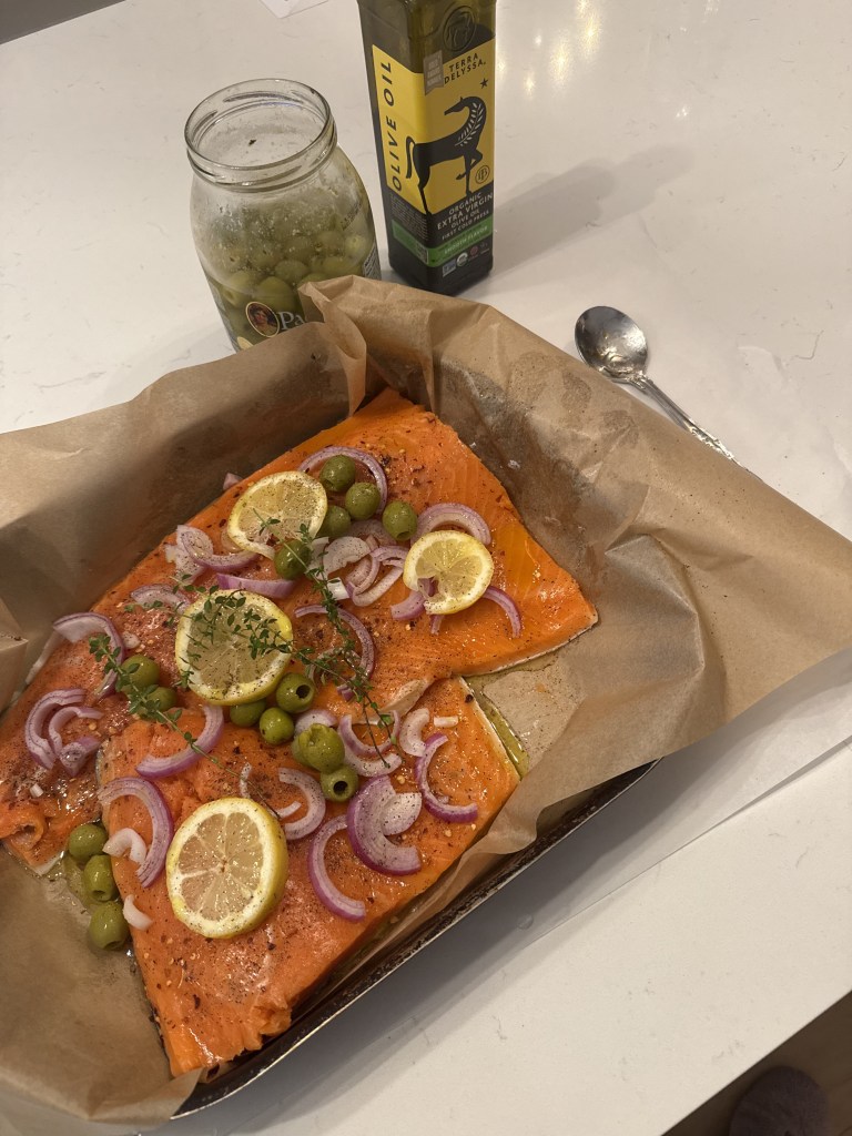 Oven-baked salmon topped with lemon, red onion, green olives and fresh thyme.